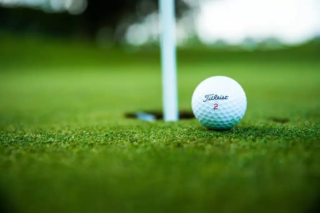 Titleist golf ball next to the hole on a putting green