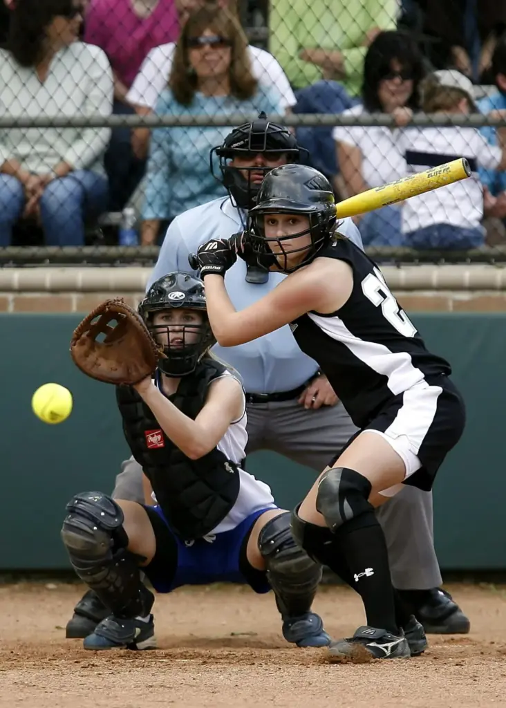 Young softball player focused at the plate as the pitch arrives