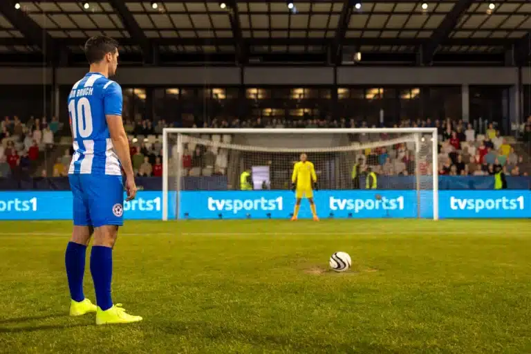 Soccer player lining up a free kick under pressure in front of a packed crowd